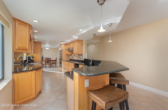 kitchen with hanging light fixtures, light tile patterned floors, sink, kitchen peninsula, and a breakfast bar