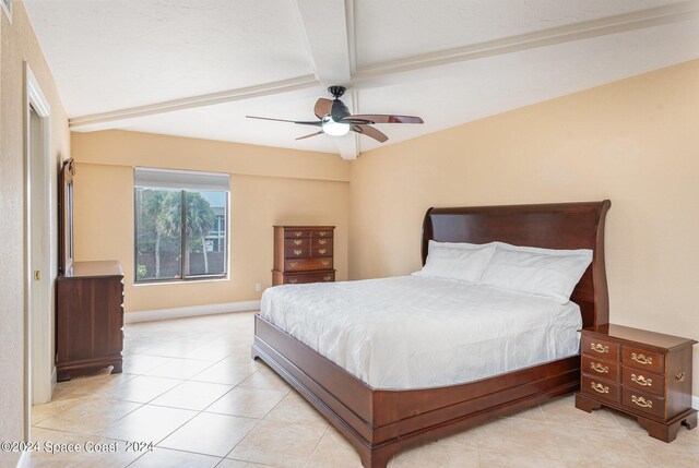 bedroom with ceiling fan, light tile patterned floors, and beam ceiling