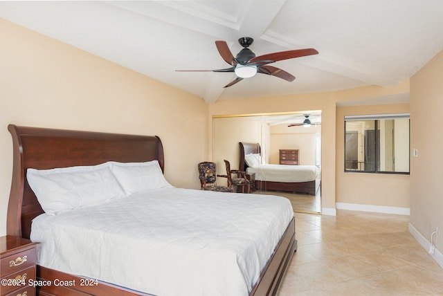 bedroom featuring a closet, ceiling fan, light tile patterned floors, and beamed ceiling