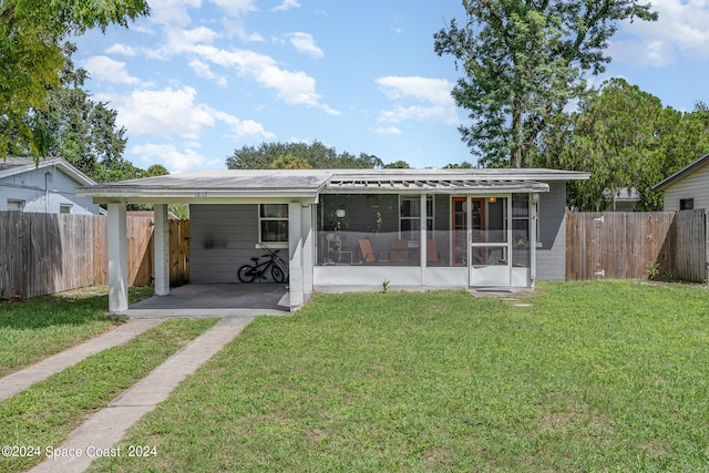 rear view of property with a sunroom, a lawn, and a carport