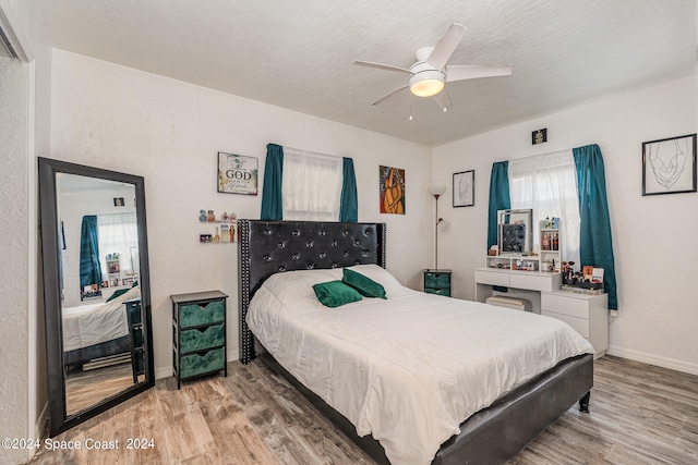 bedroom featuring light wood-type flooring, ceiling fan, and a textured ceiling