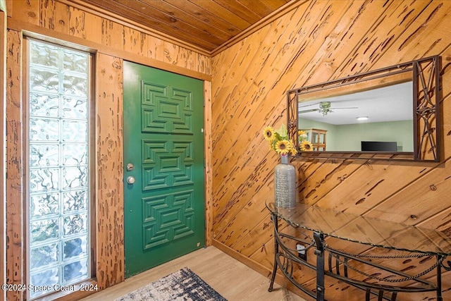 foyer entrance with ceiling fan, wood-type flooring, and wooden walls