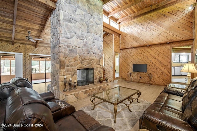 living room featuring a fireplace, light hardwood / wood-style flooring, wood walls, ceiling fan, and wood ceiling