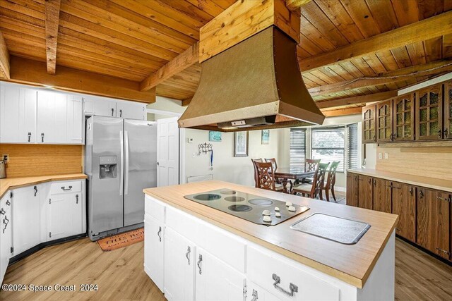 kitchen featuring beamed ceiling, stainless steel fridge, and white cabinets