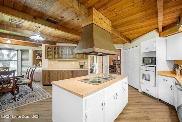 kitchen with island range hood, white oven, electric cooktop, and white cabinetry