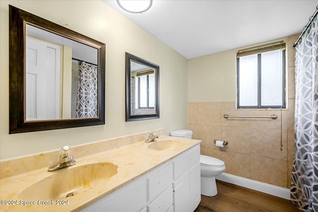 bathroom featuring toilet, walk in shower, hardwood / wood-style floors, vanity, and tile walls