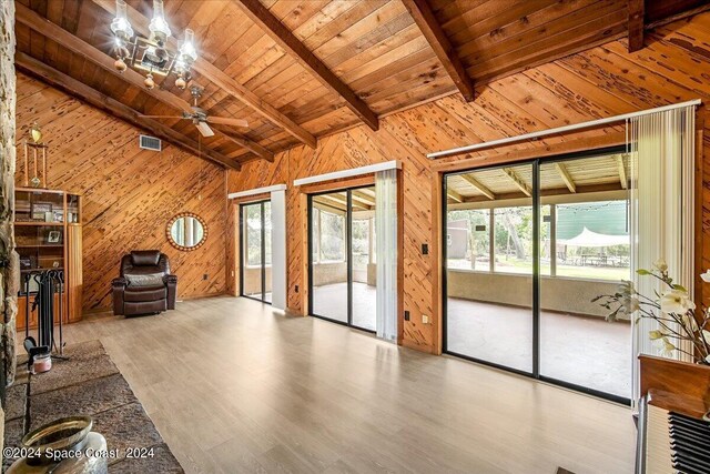 unfurnished room featuring ceiling fan with notable chandelier, a healthy amount of sunlight, and light hardwood / wood-style floors