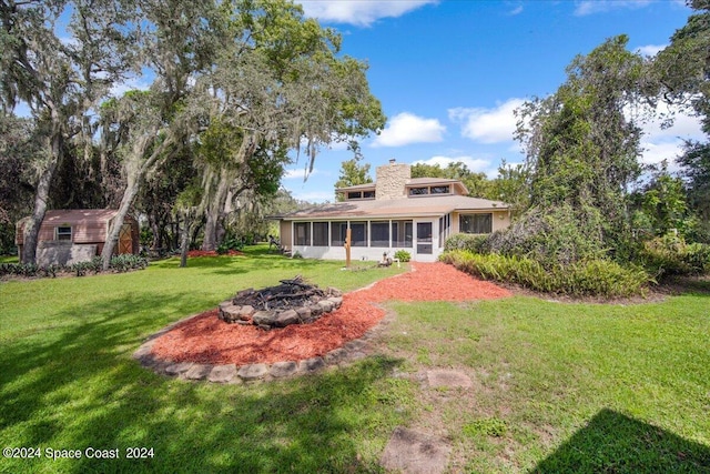 view of yard featuring an outdoor fire pit, a storage shed, and a sunroom