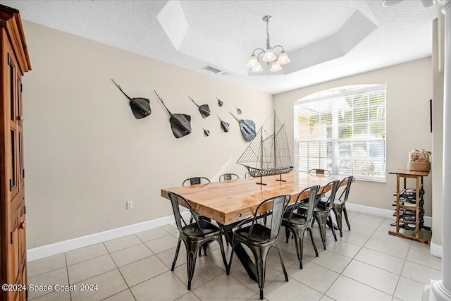 tiled dining area featuring a textured ceiling, a notable chandelier, and a tray ceiling