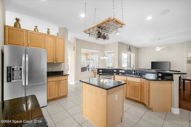 kitchen featuring ceiling fan with notable chandelier, pendant lighting, a center island, stainless steel appliances, and sink