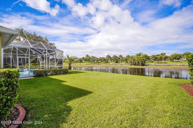 view of yard with glass enclosure and a water view