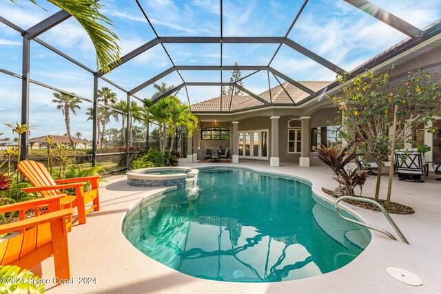 view of pool featuring glass enclosure, an in ground hot tub, ceiling fan, and a patio area