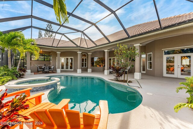 view of swimming pool with a lanai, an in ground hot tub, french doors, and a patio area