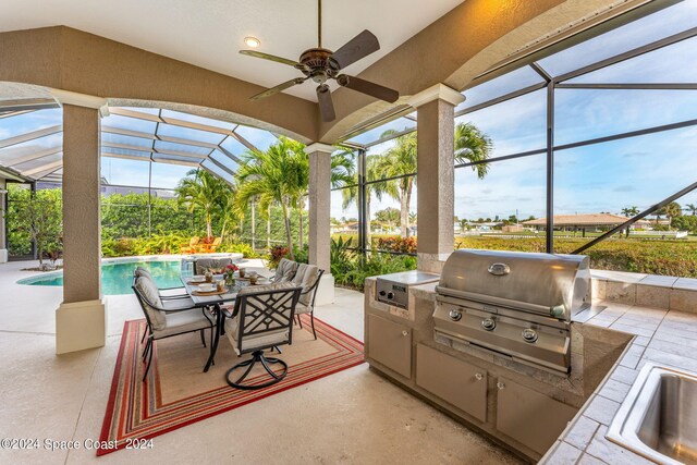 view of patio with glass enclosure, ceiling fan, and area for grilling