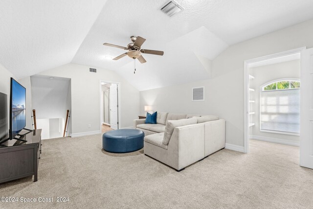 living room featuring lofted ceiling, ceiling fan, light carpet, and a textured ceiling