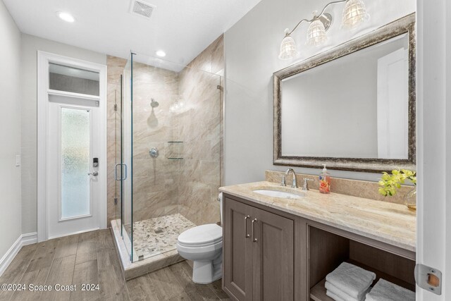 bathroom with hardwood / wood-style floors, walk in shower, toilet, and vanity