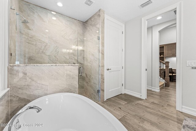 bathroom with hardwood / wood-style flooring and independent shower and bath