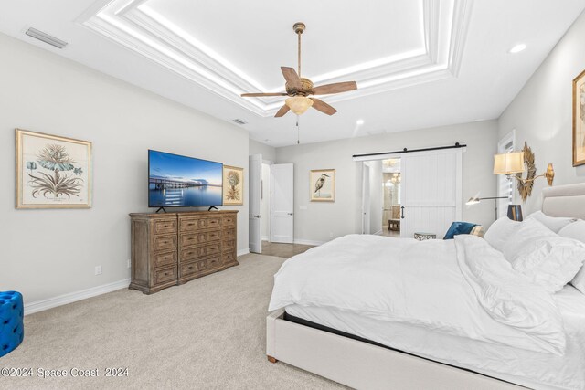 carpeted bedroom featuring a raised ceiling, ceiling fan, and a barn door