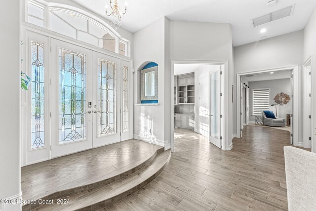 entryway featuring a high ceiling, hardwood / wood-style floors, a chandelier, and french doors