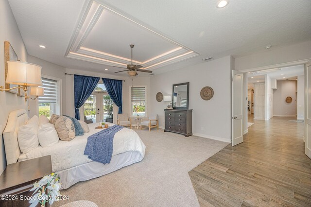 bedroom with a raised ceiling, french doors, access to outside, carpet flooring, and ceiling fan