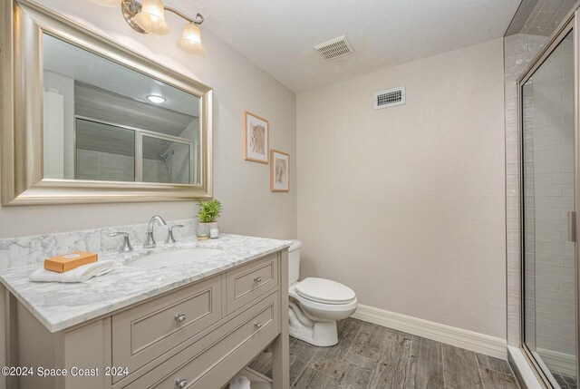 bathroom with an enclosed shower, toilet, hardwood / wood-style flooring, and vanity