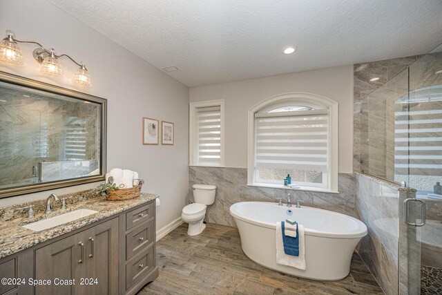 full bathroom featuring toilet, separate shower and tub, vanity, tile walls, and hardwood / wood-style flooring