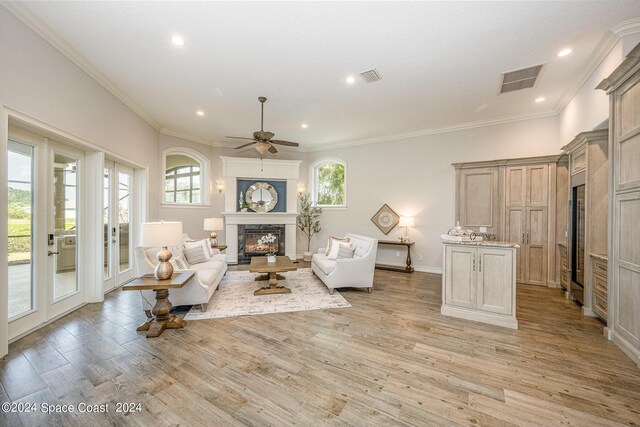 living room featuring light wood-type flooring, ceiling fan, crown molding, and french doors