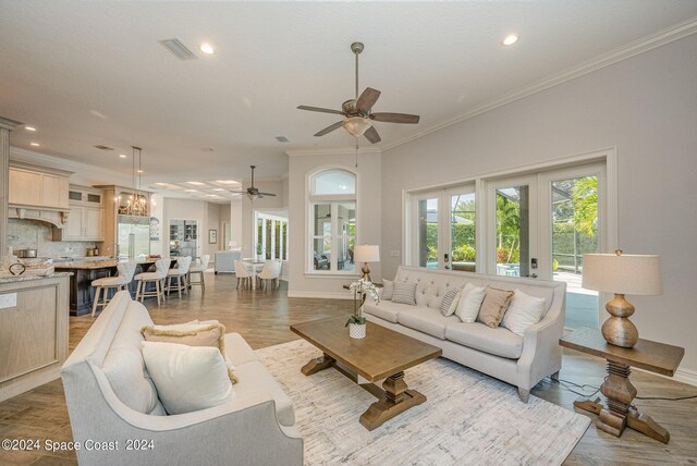 living room with ceiling fan, ornamental molding, french doors, and light hardwood / wood-style floors