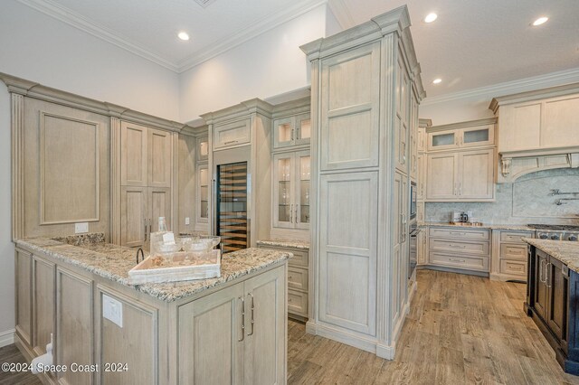 kitchen with ornamental molding, stainless steel appliances, light stone counters, and light wood-type flooring