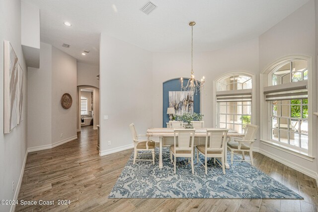 dining area featuring a towering ceiling, a chandelier, and hardwood / wood-style floors