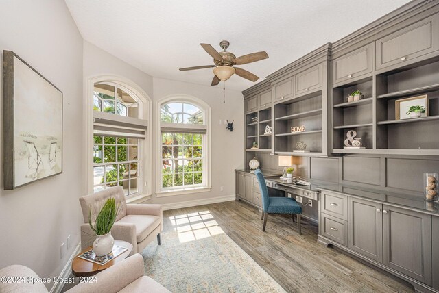 office area with light wood-type flooring, built in desk, and ceiling fan