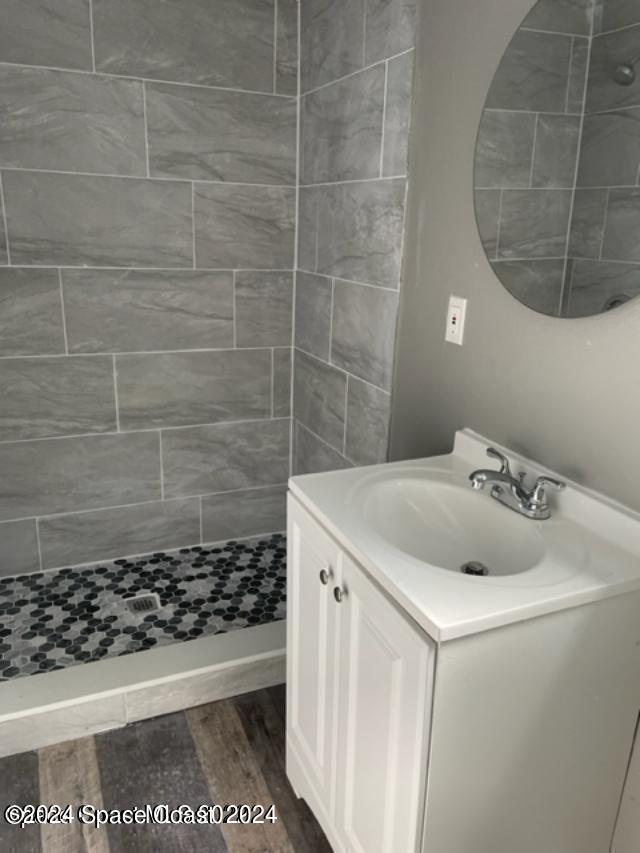 bathroom featuring tiled shower, vanity, and hardwood / wood-style floors