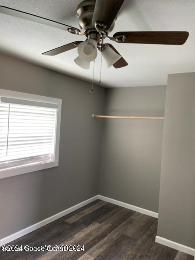 empty room with dark wood-type flooring and ceiling fan