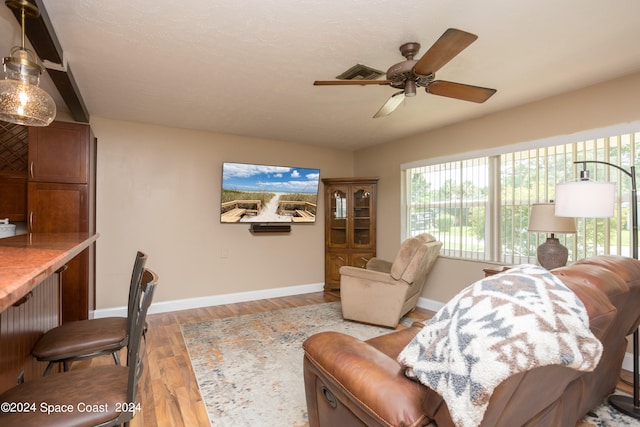 living room with hardwood / wood-style flooring, bar area, and ceiling fan