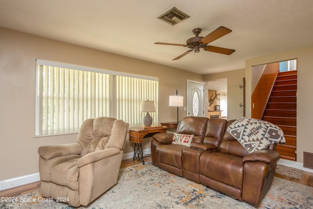 living room featuring light hardwood / wood-style flooring, a textured ceiling, and ceiling fan