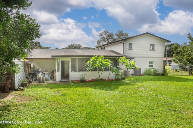 rear view of house featuring a sunroom and a lawn