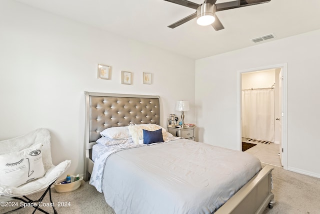 bedroom featuring ceiling fan, light carpet, and ensuite bath