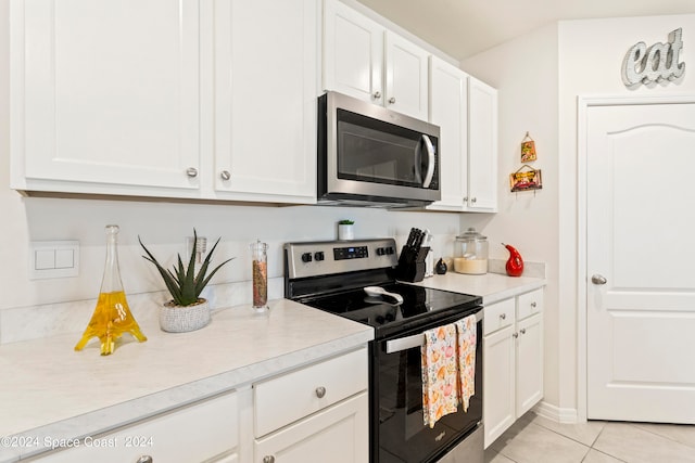 kitchen featuring white cabinetry, stainless steel appliances, and light tile patterned flooring