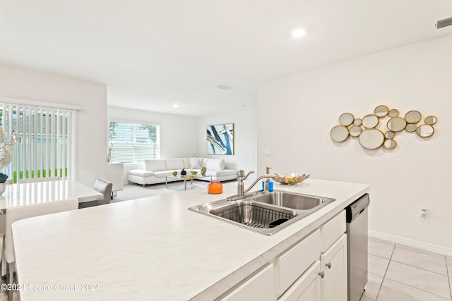 kitchen featuring a kitchen island with sink, light tile patterned floors, sink, stainless steel dishwasher, and white cabinets