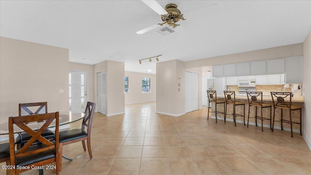 dining room featuring a textured ceiling, ceiling fan, light tile patterned floors, and rail lighting