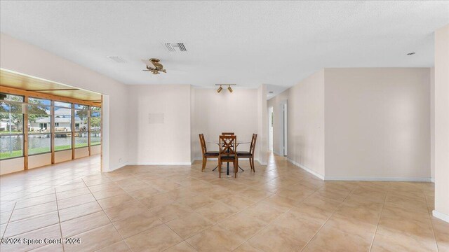 tiled spare room with ceiling fan and a textured ceiling