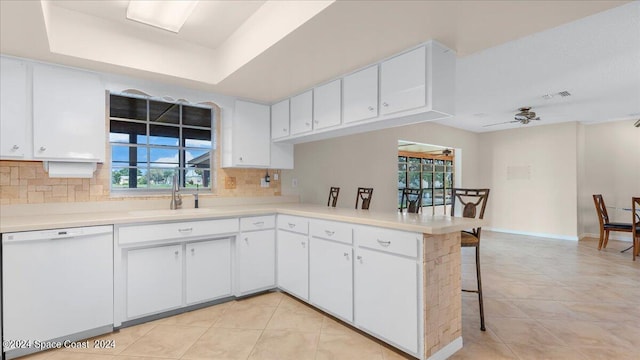 kitchen with white cabinets, dishwasher, kitchen peninsula, and backsplash