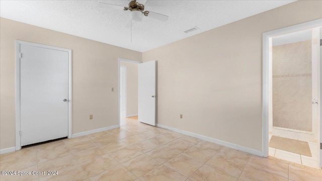 unfurnished bedroom featuring ceiling fan, light tile patterned flooring, and a textured ceiling