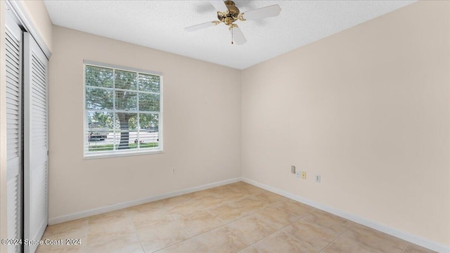 interior space featuring ceiling fan, a textured ceiling, a closet, and light tile patterned flooring