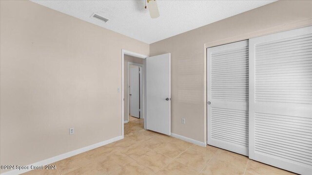 unfurnished bedroom featuring a textured ceiling, ceiling fan, and a closet