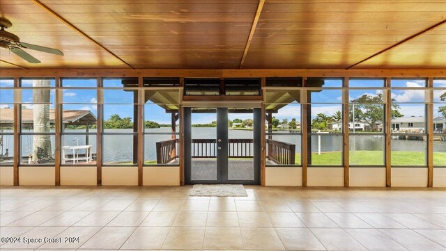 unfurnished sunroom with wood ceiling, a water view, ceiling fan, and a wealth of natural light