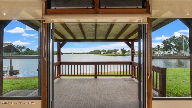 wooden terrace with a yard and a water view