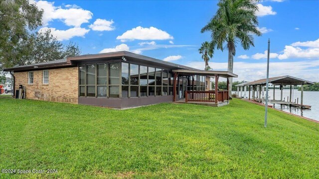 rear view of house featuring a water view and a yard