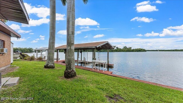 view of dock with a lawn and a water view