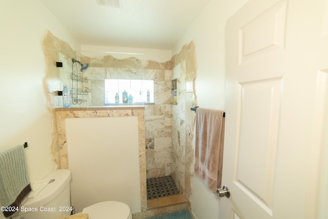 bathroom featuring tiled shower and toilet